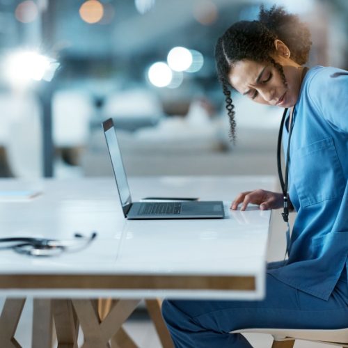 Back pain, stress and doctor in her office at the hospital working on a diagnosis or cure. Computer, healthcare and female medical worker with a muscle sprain, ache or inflammation at medicare clinic.